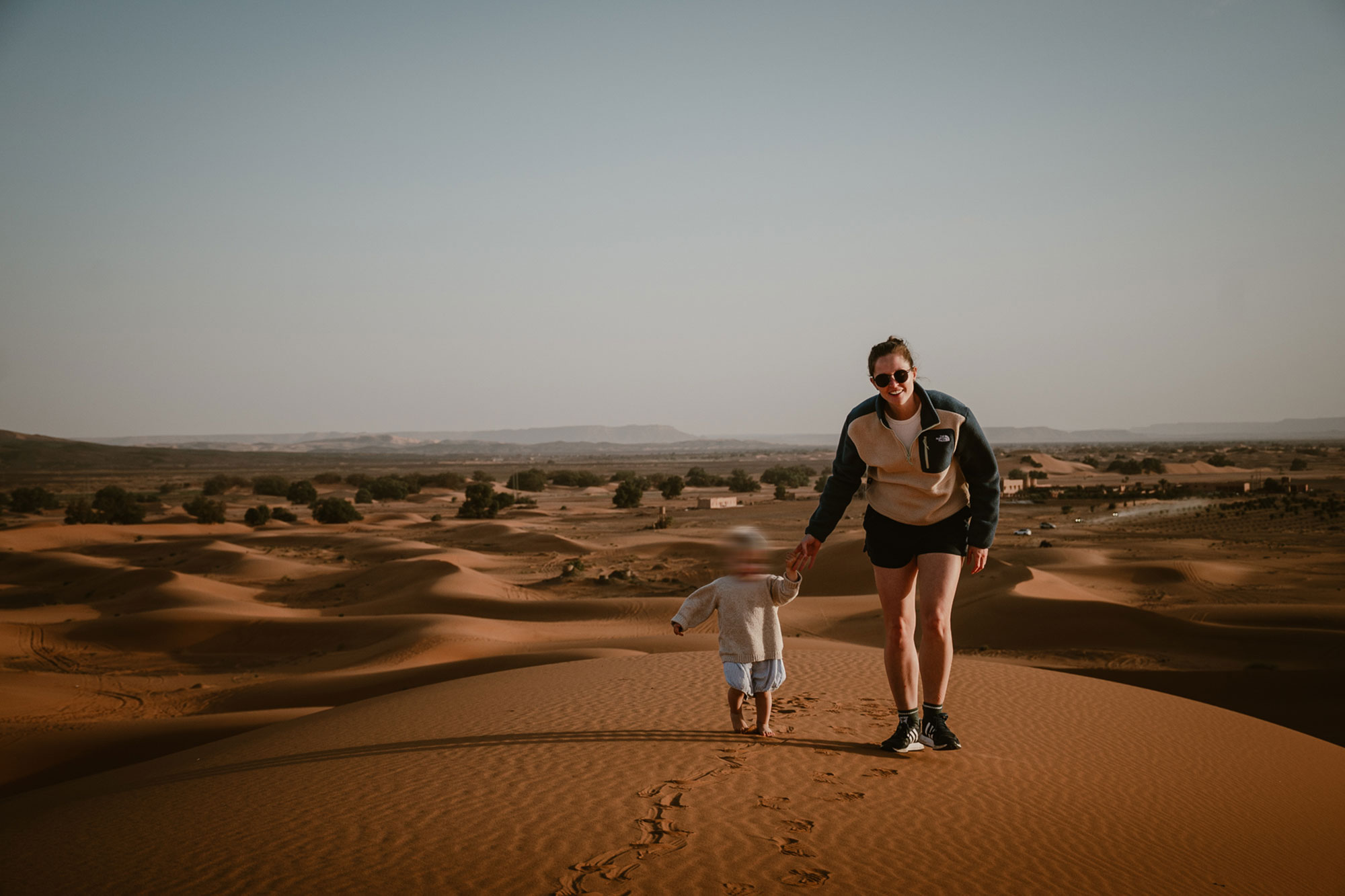 Mother and daughter playing and running in Moroccon dessert at sundown.